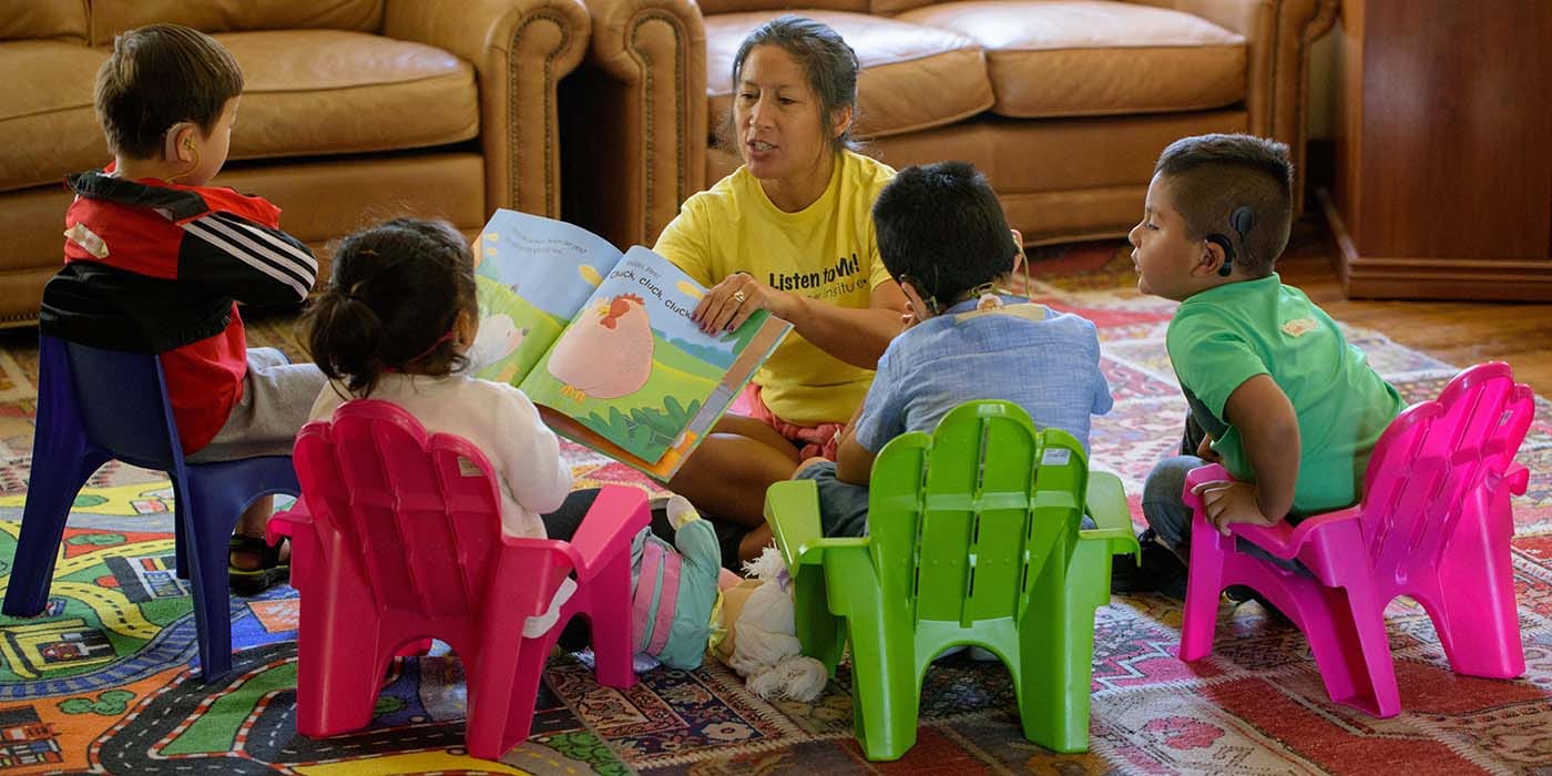 Instructor showing a picture book to four children with cochlear implants